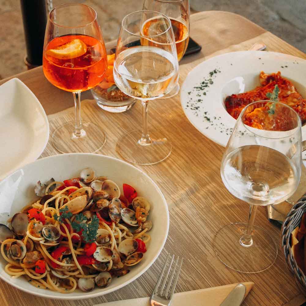 Två djupa tallrikar står på ett restaurangbord, en med musslor och en pastatallrik med lasagne.