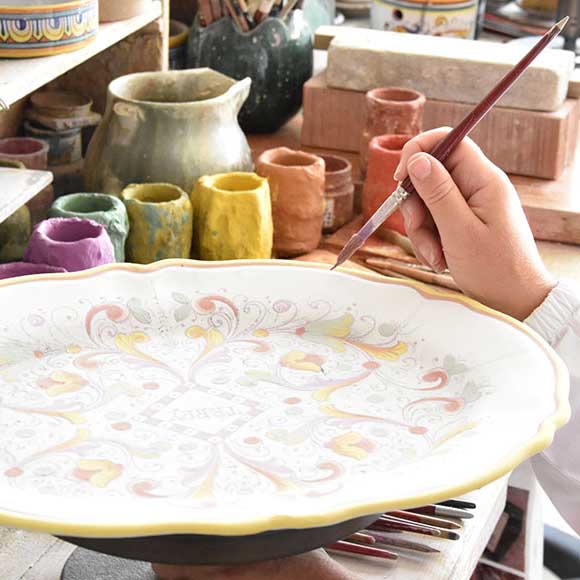 En hantverkare från GP Deruta målar en tallrik från det kända bordsporslinmärket.
